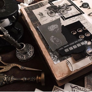May include: A vintage-style scrapbook with torn paper, illustrations, and handwritten notes. The pages are aged with a sepia tone. A pen holder, scissors, and a wax seal are also visible, suggesting a theme of journaling and ephemera.