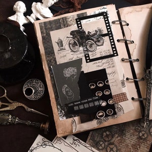 May include: A vintage-themed scrapbook with a collage of images, including an antique car, film strip, and typewriter keys. The pages are aged with a sepia tone, and the text "with brave wings she flies" is visible.