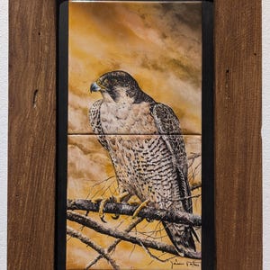 May include: A rectangular wall art piece featuring a painting of a peregrine falcon perched on a branch against a golden sky, composed of two stacked ceramic tiles set within a rustic, dark brown wooden frame with a visible signature.
