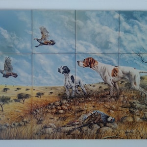 May include: A painting of two white and brown hunting dogs in a field with a blue sky and white clouds. One dog is pointing at a dead bird on the ground. The other dog is looking up at a bird flying in the sky.