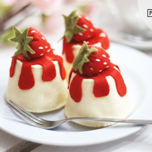 Peut inclure: Trois cupcakes en feutre blanc avec du glaçage en feutre rouge et des fraises en feutre rouge sur le dessus. Les cupcakes sont sur une assiette blanche avec une fourchette en argent.