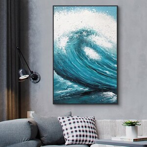 May include: A framed abstract painting of a large blue wave crashing against a white background. The wave is painted with thick brushstrokes and has a textured surface.