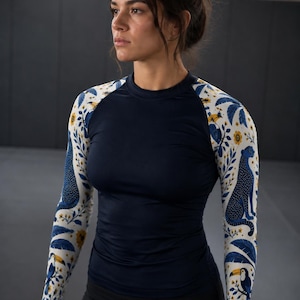 Peut inclure: Un haut de sport à manches longues avec un torse bleu marine uni et des manches blanches ornées d'un motif répétitif de léopards bleus, de toucans et de fleurs jaunes. Le vêtement présente une encolure ronde et des manches raglan ajustées.