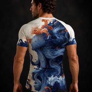 Op de afbeelding: Een sportshirt met korte mouwen en een gedetailleerde grafische print van een blauwe octopus verweven met kolkende oceaangolven en oranje spatten. Het kledingstuk heeft witte raglanmouwen en een nauwsluitend model.