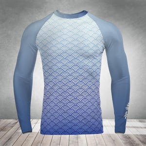 May include: A long-sleeved shirt with a blue and white wave pattern on the torso. The sleeves are solid light blue, and there is Japanese text on the right sleeve. The shirt has a crew neck.