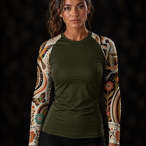 Op de afbeelding: Een shirt met lange mouwen met een effen olijfgroene romp en crèmekleurige mouwen met een kleurrijke grafische print van vlinders, vogels en bloemmotieven in tinten oranje, petrol en bruin, afgewerkt met een ronde halslijn.