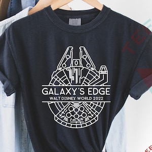 May include: Black t-shirt with a white graphic of the Millennium Falcon and the text "Galaxy's Edge Walt Disney World 2022".