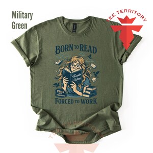 May include: Military green t-shirt with the text "BORN TO READ" above an illustration of a person reading a book. The illustration includes the text "Fourth Wing" and "PAGES OVER PAYCHECKS".