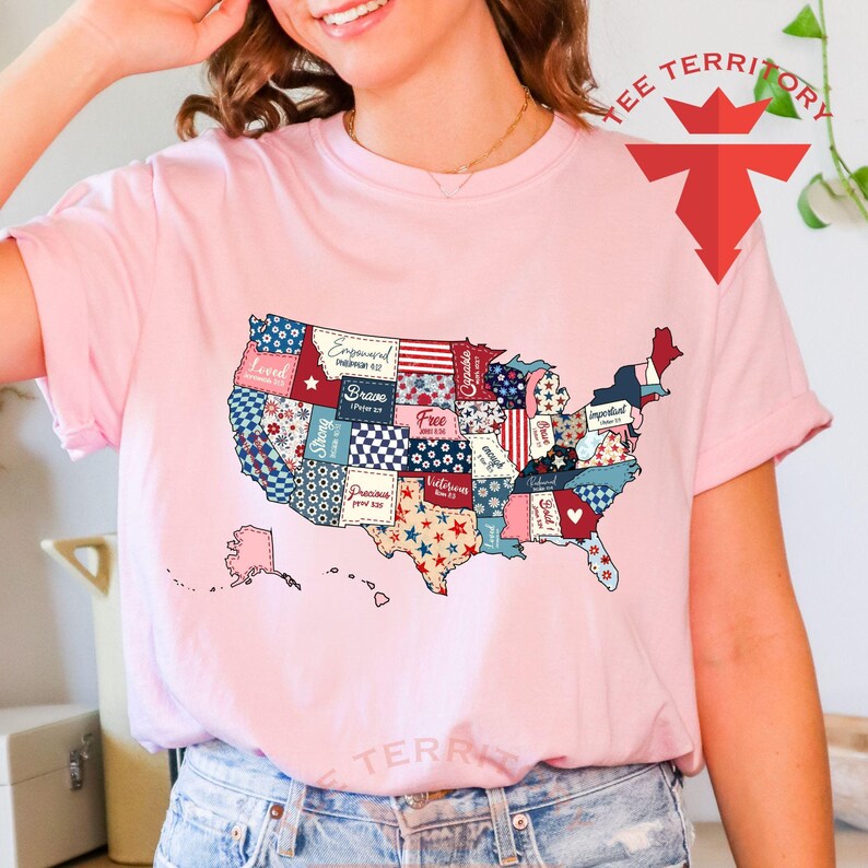 Pu&ograve; includere: Una maglietta rosa con un design a patchwork degli Stati Uniti. Ogni stato &egrave; un motivo diverso con parole come "Loved", "Strong", "Brave", "Free", "Victorious", "Precious", "Empowered", "Important", "Celebrated" e "Blessed".