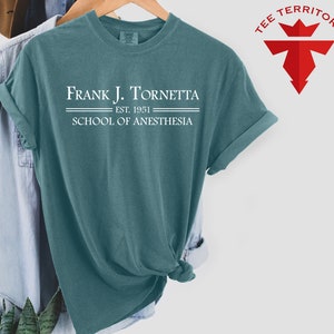 May include: A teal blue t-shirt with the text "Frank J. Tornetta Est. 1951 School of Anesthesia" printed in white.