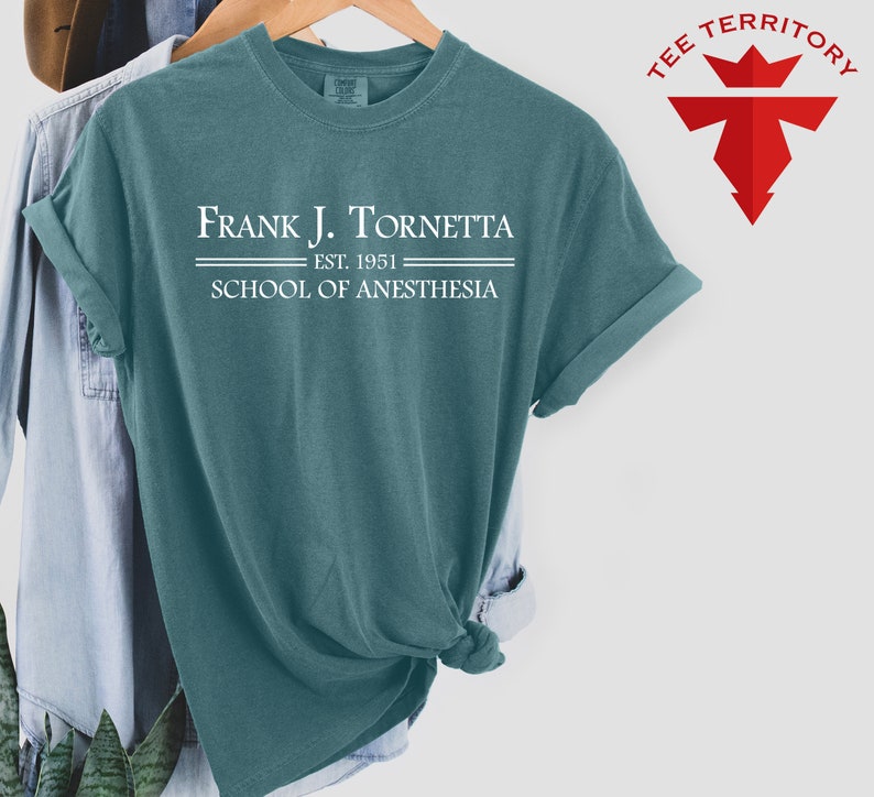 May include: A teal blue t-shirt with the text "Frank J. Tornetta Est. 1951 School of Anesthesia" printed in white.