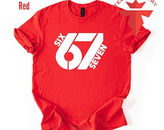 May include: A red t-shirt with the white text "SIX 67 SEVEN" printed on the front. The shirt has short sleeves and a crew neck. The words "TEE TERRITORY" are printed on the top right.