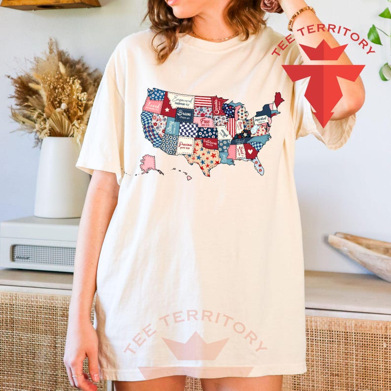 Pu&ograve; includere: Una maglietta bianca con un design a patchwork degli Stati Uniti d'America. Ogni stato &egrave; rappresentato da un diverso motivo di tessuto con colori rosso, bianco e blu. La maglietta ha le parole "Tee Territory" stampate in basso.