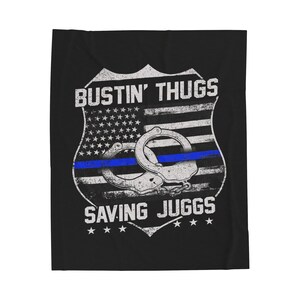 May include: A black and white graphic design of a police badge with an American flag background. The badge has the text "Bustin' Thugs Saving Juggs" and handcuffs.