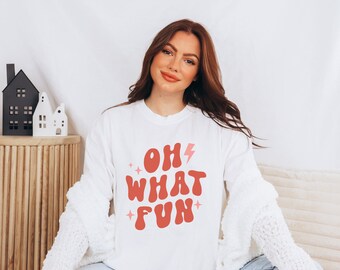 May include: White long-sleeve sweatshirt with a pink and red graphic that says "Oh What Fun" with a lightning bolt.