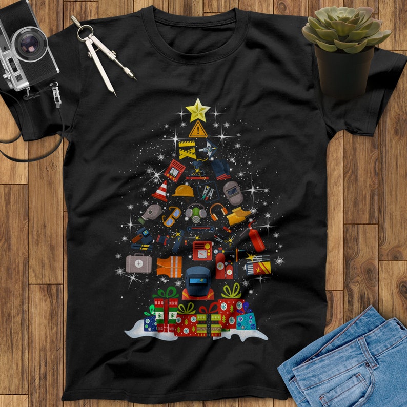 May include: Black t-shirt with a Christmas tree design made up of various tools and equipment. The tree is topped with a star and has presents at the bottom.