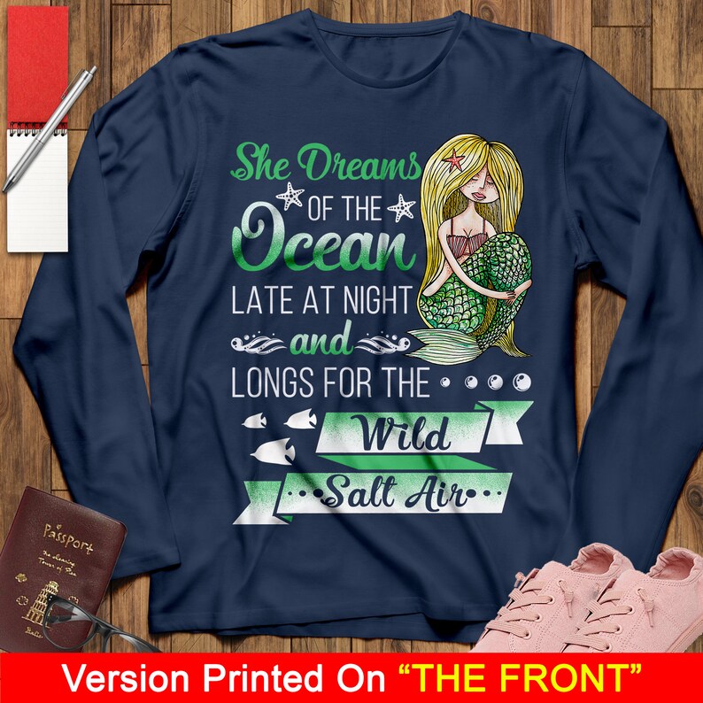 May include: Navy blue long-sleeve shirt with a mermaid illustration and the text "She Dreams of the Ocean Late at Night and Longs for the Wild Salt Air".