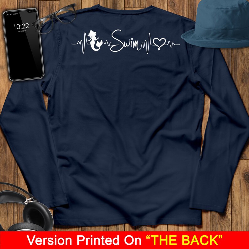 Puede incluir: Camiseta de manga larga azul marino con un gr&aacute;fico de sirena blanca y el texto "Swim" en un dise&ntilde;o de latido del coraz&oacute;n. El dise&ntilde;o est&aacute; impreso en la parte posterior de la camiseta.
