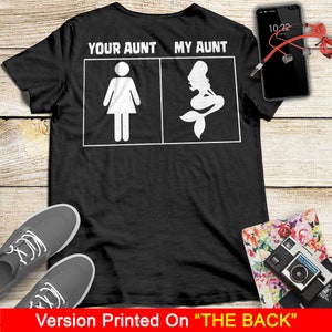 Puede incluir: Camiseta negra con texto blanco que dice "Your Aunt My Aunt" con una figura de palo de una mujer a la izquierda y una sirena a la derecha.