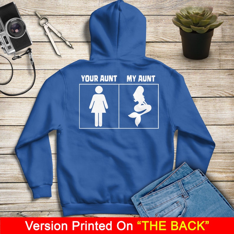 Puede incluir: Una sudadera con capucha azul real con texto blanco que dice "Your Aunt" y "My Aunt" con una silueta de una mujer y una sirena en las casillas debajo del texto. El texto est&aacute; impreso en la parte posterior de la sudadera con capucha.