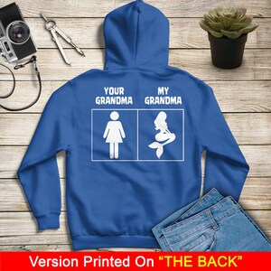 Może przedstawiać: Niebieska bluza z kapturem z białym napisem "Your Grandma" i "My Grandma" oraz ilustracją postaci i syreny.