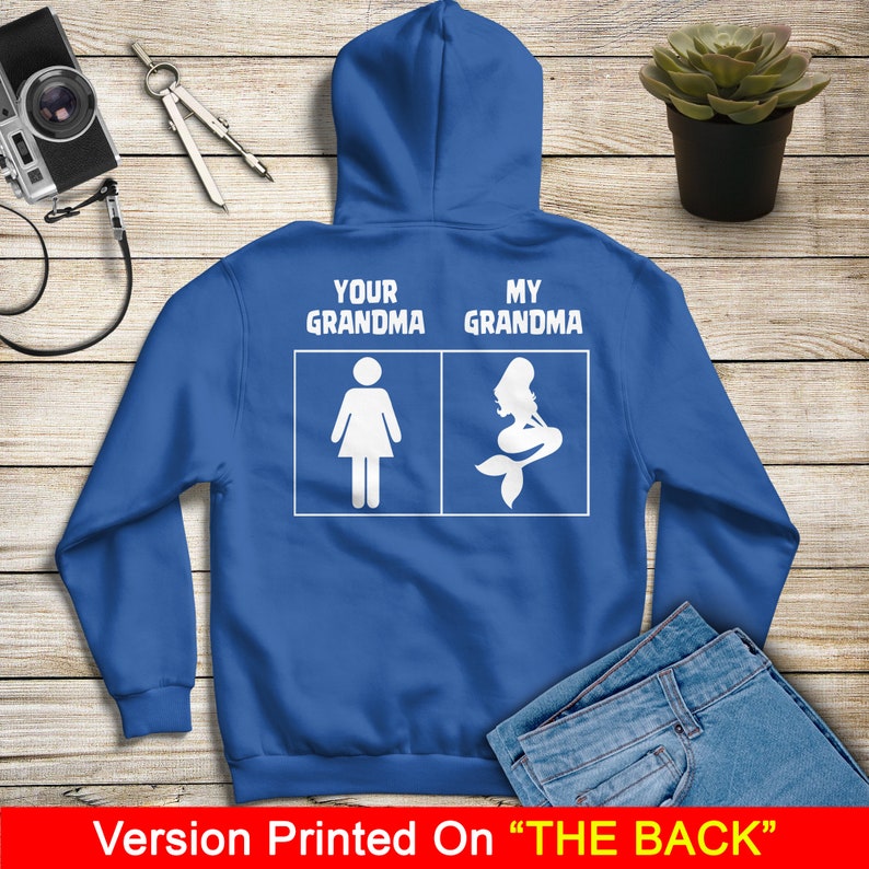 Może przedstawiać: Niebieska bluza z kapturem z białym napisem "Your Grandma" i "My Grandma" oraz ilustracją postaci i syreny.