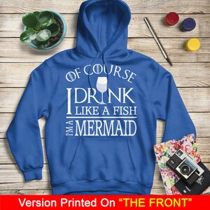 May include: A royal blue hoodie with a white graphic that says "Of course I drink like a fish, I'm a mermaid" with a white wine glass with a mermaid tail design.