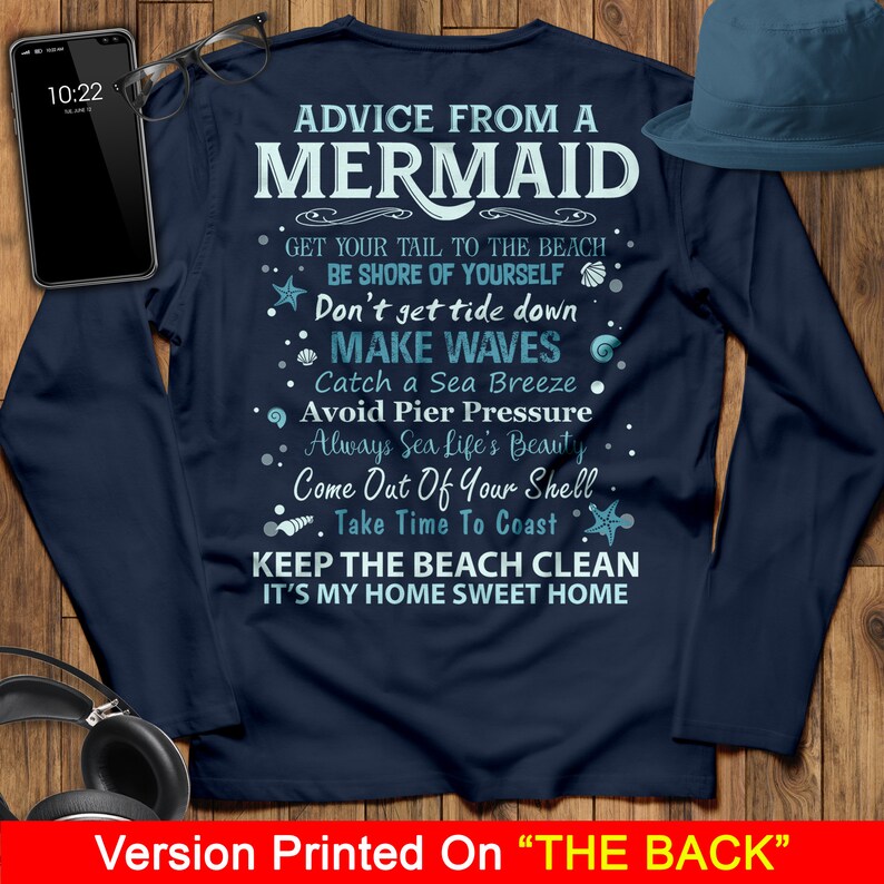 May include: A navy blue long-sleeved t-shirt with white text that reads "Advice from a Mermaid" and includes a list of tips for enjoying the beach. The text includes phrases like "Get your tail to the beach", "Be shore of yourself", "Don't get tide down", "Make waves", "Catch a sea breeze", "Avoid pier pressure", "Always sea life's beauty", "Come out of your shell", "Take time to coast", "Keep the beach clean", and "It's my home sweet home".