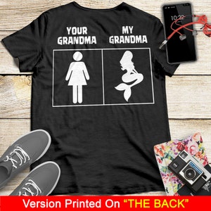 Może przedstawiać: Czarny T-shirt z białym tekstem, kt&oacute;ry brzmi "Your Grandma" i "My Grandma" z ilustracją postaci i syreny.