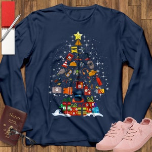 May include: A navy blue long-sleeved t-shirt with a Christmas tree design made up of construction and welding tools. The tree is decorated with a yellow star and red and green presents.