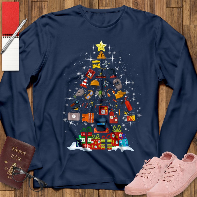 May include: A navy blue long-sleeved t-shirt with a Christmas tree design made up of construction and welding tools. The tree is decorated with a yellow star and red and green presents.