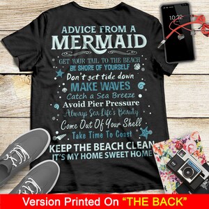 May include: Black t-shirt with white text that reads "Advice from a Mermaid" and includes a list of tips for beachgoers. The text includes phrases like "Get your tail to the beach", "Don't get tide down", "Make waves", "Catch a sea breeze", "Avoid pier pressure", "Always sea life's beauty", "Come out of your shell", "Take time to coast", "Keep the beach clean", and "It's my home sweet home".
