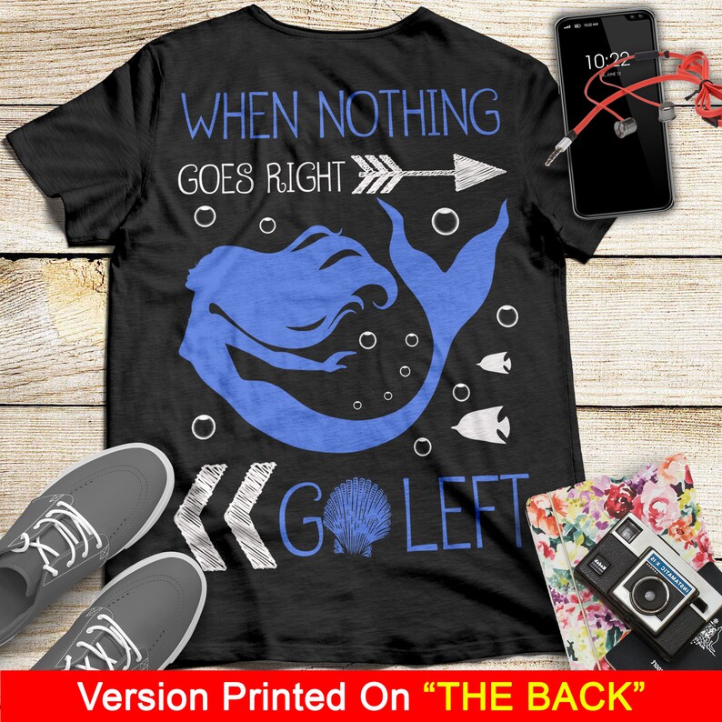 May include: Black t-shirt with a white mermaid design and the text "When nothing goes right, go left". The mermaid is blue and has a white seashell in her tail. The text is written in a handwritten style.