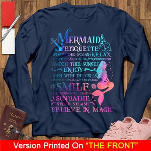 May include: A navy blue long-sleeve t-shirt with a colorful mermaid graphic and the text "Mermaid Etiquette" with a list of mermaid rules. The graphic includes a mermaid with a pink tail and a blue and purple ombre effect.