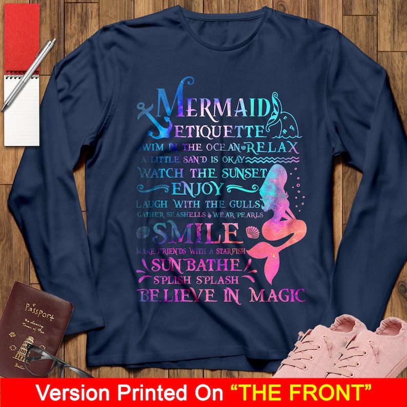 May include: A navy blue long-sleeve t-shirt with a colorful mermaid graphic and the text "Mermaid Etiquette" with a list of mermaid rules. The graphic includes a mermaid with a pink tail and a blue and purple ombre effect.