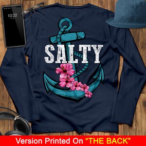 May include: Navy blue long-sleeve shirt with a white anchor and the word "SALTY" printed on the back. Pink hibiscus flowers are around the anchor.