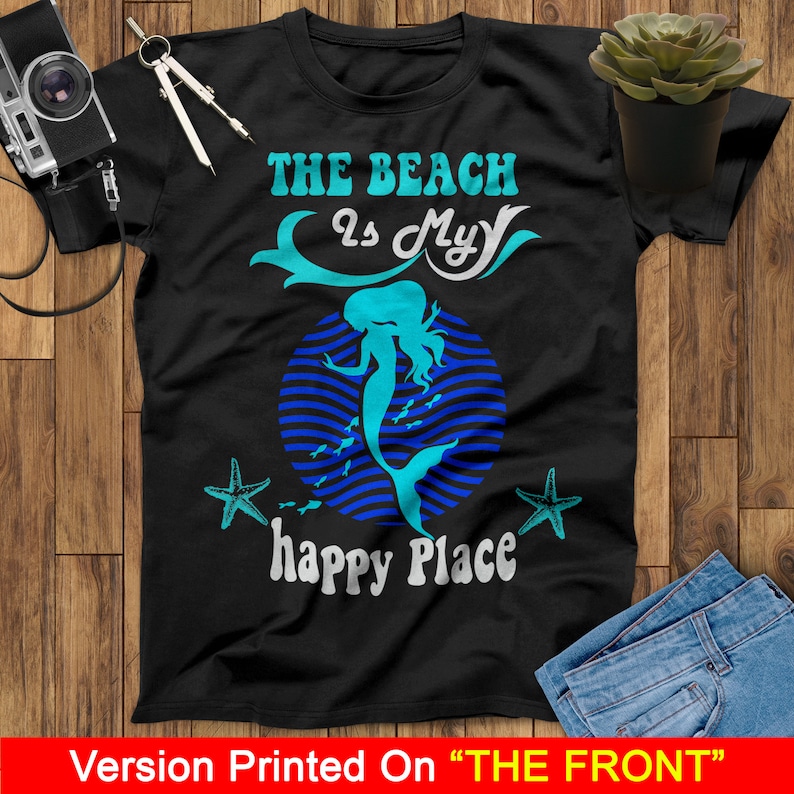 Peut inclure: T-shirt noir avec un motif de sir&egrave;ne bleu et blanc. Le texte "The Beach Is My Happy Place" est imprim&eacute; sur le t-shirt.