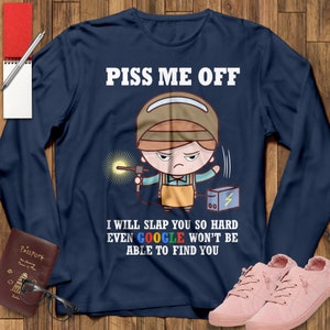 May include: A navy blue long-sleeved t-shirt with a cartoon illustration of a welder wearing a hard hat and holding a welding torch. The text "PISS ME OFF" is printed in white above the illustration. Below the illustration, the text "I WILL SLAP YOU SO HARD EVEN GOOGLE WON'T BE ABLE TO FIND YOU" is printed in white.