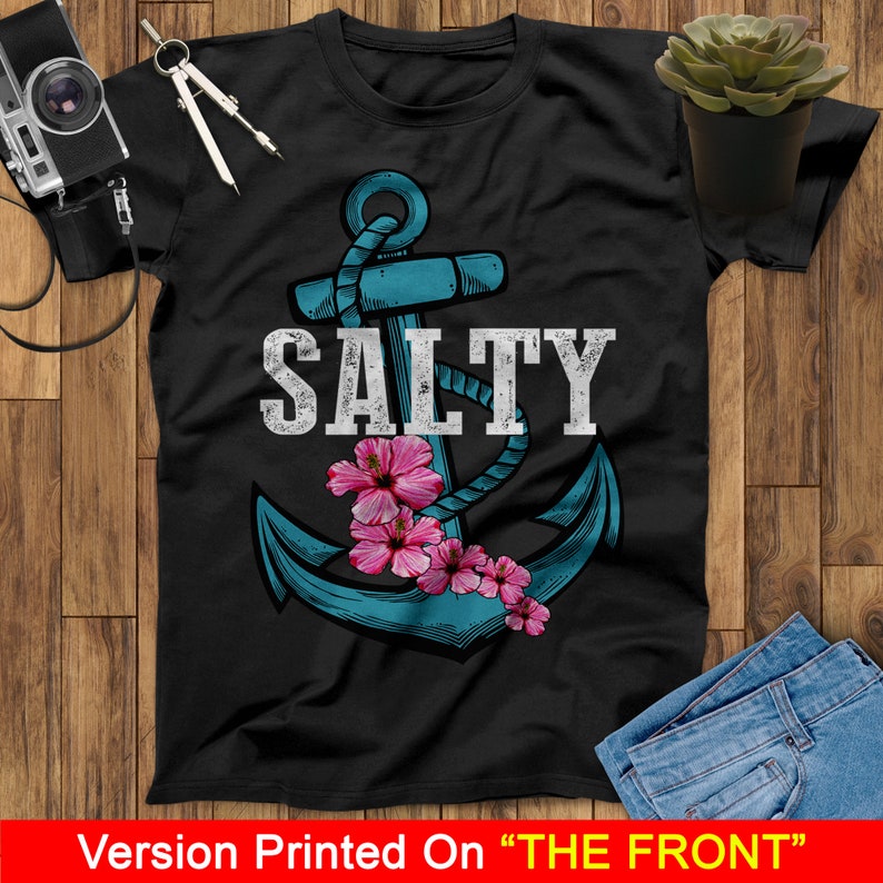 May include: A black t-shirt with a blue anchor and pink flowers. The text "SALTY" is printed in white above the anchor.