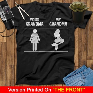 Może przedstawiać: Czarny T-shirt z białym tekstem, kt&oacute;ry brzmi "Your Grandma" i "My Grandma". Lewa strona koszulki przedstawia figurkę kobiety. Prawa strona koszulki przedstawia sylwetkę syreny.