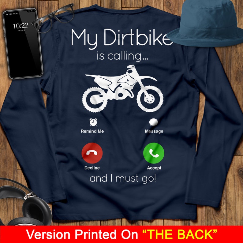 May include: A navy blue long-sleeved t-shirt with a white graphic of a dirt bike and a phone screen with the text "My Dirtbike is calling... Remind Me Message Decline Accept and I must go!" printed on the back.