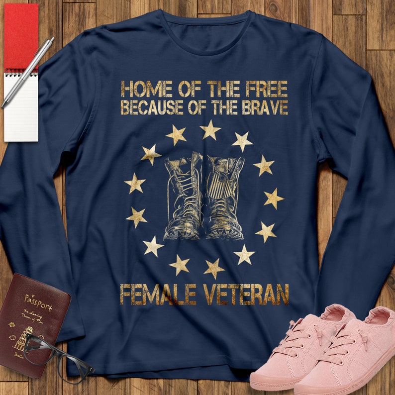 Puede incluir: Camiseta de manga larga azul marino con un estampado dorado de un c&iacute;rculo de estrellas que rodea dos botas militares. El texto "HOME OF THE FREE BECAUSE OF THE BRAVE" est&aacute; por encima de las botas y el texto "FEMALE VETERAN" est&aacute; por debajo de las botas.