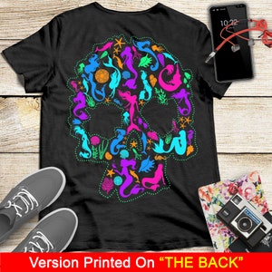 May include: Black t-shirt with a colorful mermaid skull design printed on the back. The skull is made up of mermaids, seashells, starfish, and other ocean-themed elements.