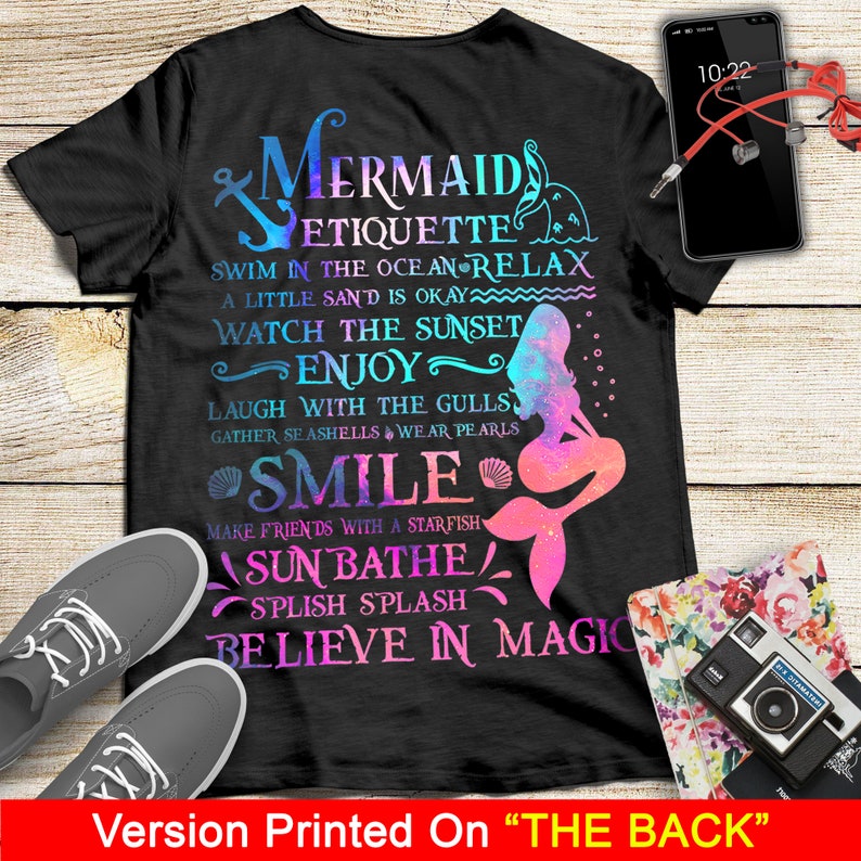May include: Black t-shirt with a mermaid graphic and text that reads "Mermaid Etiquette: Swim in the ocean & relax, a little sand is okay, watch the sunset, enjoy, laugh with the gulls, gather seashells & wear pearls, smile, make friends with a starfish, sunbathe, splish splash, believe in magic".