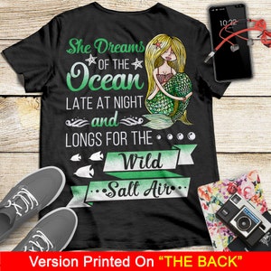 May include: Black t-shirt with a mermaid illustration and the text "She Dreams of the Ocean Late at Night and Longs for the Wild Salt Air".