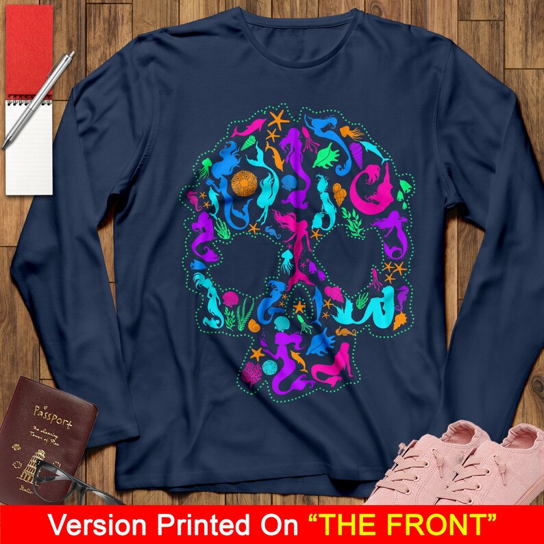 May include: A navy blue long-sleeved t-shirt with a colorful mermaid skull design. The skull is made up of mermaids, seashells, starfish, and other ocean-themed imagery.