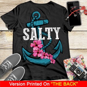 May include: A black t-shirt with a blue anchor and the word "SALTY" in white text. The anchor is surrounded by pink hibiscus flowers.