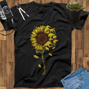 May include: Black t-shirt with a yellow sunflower and silhouette elephants. The text "You are my sunshine" is written vertically on the right side of the sunflower.
