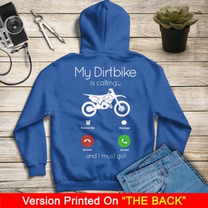 May include: Blue hooded sweatshirt with a white graphic of a dirt bike with a phone interface. The text on the graphic reads "My Dirtbike is calling... Remind Me Message Decline Accept and I must go!"