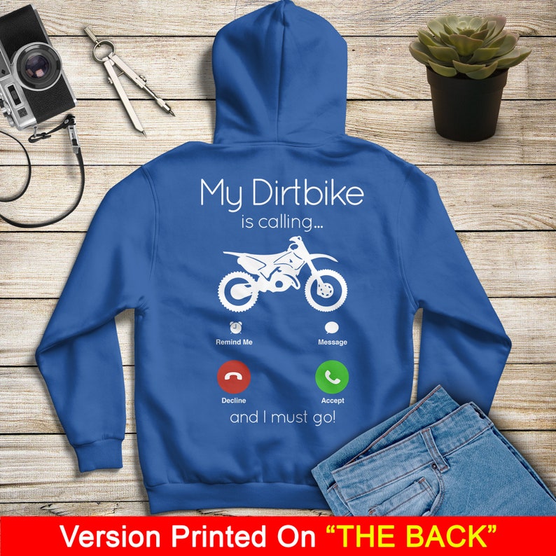 May include: Blue hooded sweatshirt with a white graphic of a dirt bike with a phone interface. The text on the graphic reads "My Dirtbike is calling... Remind Me Message Decline Accept and I must go!"